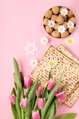Yahudi bayramı tebrik kartı konsepti. Üzerinde matza, fındık, lale ve papatya çiçekleri var. Seder Pesach bahar tatili arka planı, üst görünüm, kopyalama alanı.
