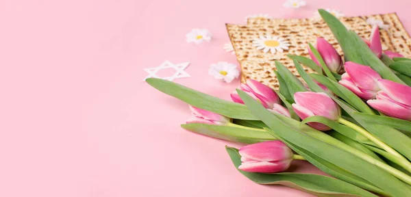 ユダヤ人の休日ピンクのテーブルの上にマツア ナッツ チューリップやデイジーの花と過越のグリーティングカードの概念 Seder Pesach春休みの背景 コピースペース — ストック写真