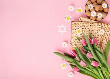Yahudi bayramı tebrik kartı konsepti. Üzerinde matza, fındık, lale ve papatya çiçekleri var. Seder Pesach bahar tatili arka planı, üst görünüm, kopyalama alanı.
