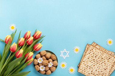 Yahudi bayramı tebrik kartı konsepti. Matza, fındık, lale ve papatya çiçekli mavi masa. Seder Pesach bahar tatili arka planı, üst görünüm, kopyalama alanı.