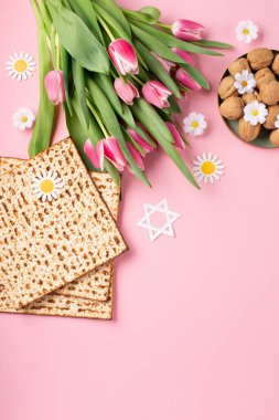 Yahudi bayramı tebrik kartı konsepti. Üzerinde matza, fındık, lale ve papatya çiçekleri var. Seder Pesach bahar tatili arka planı, üst görünüm, kopyalama alanı.