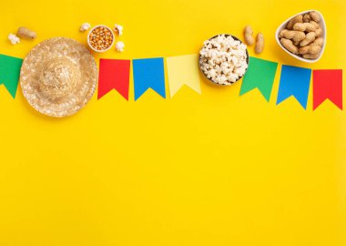 Brezilya Karnavalı Festa Junina Yaz Festivali konsepti. Brezilya hasır şapkası, patlamış mısır, fıstık ve sarı arka planda renkli bayraklar, üst manzara. Tebrik Kartı, Davetiye veya Tatil Posteri Tasarımı