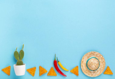 Geleneksel Meksika cipsleri, kırmızı biber, kaktüs ve mavi arka planda şapkalı Meksika arka plan şenliği. Cinco de Mayo (5 Mayıs) kutlama konsepti. Üst görünüm, alanı kopyala.