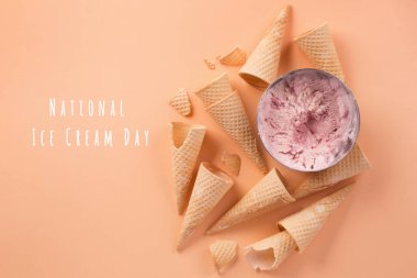 Ulusal dondurma günü 17 Temmuz konsepti. Ev yapımı yoğurt çilekli dondurma kepçeleri, tatlı waffle külahları, pastel pembe arka plan. Sağlıklı düşük kalorili yaz tatlısı, üst manzara.