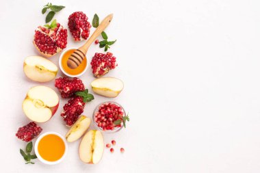 Rosh Hashanah, Jewish New Year Autumn Holiday Concept. Apples, Honey, Pomegranate, Traditional Products for Celebration on White Stone Background.