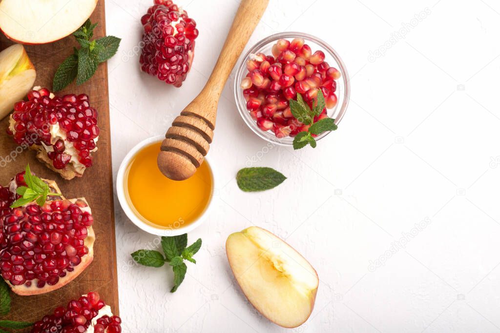 Rosh Hashanah, Jewish New Year Autumn Holiday Concept. Apples, Honey, Pomegranate, Traditional Products for Celebration on White Stone Background.