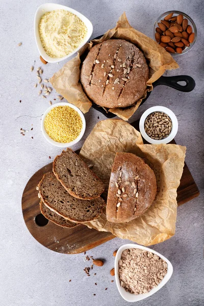 Gluten Free Homemade Bread. Healthy eating, dieting, balanced food concept. Cereals gluten-free, millet, quinoa, almond, buckwheat, flax seeds, sunflower seeds on grey background. Ancient grain food.