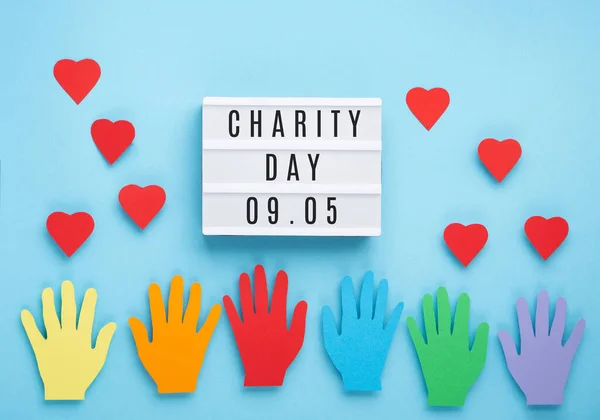 International Day of Charity, 5 September. Tolerance, kindness, cooperative, friendship, charity, humanitarian aid day concept. Colorful hands on blue background, copy space, top view.