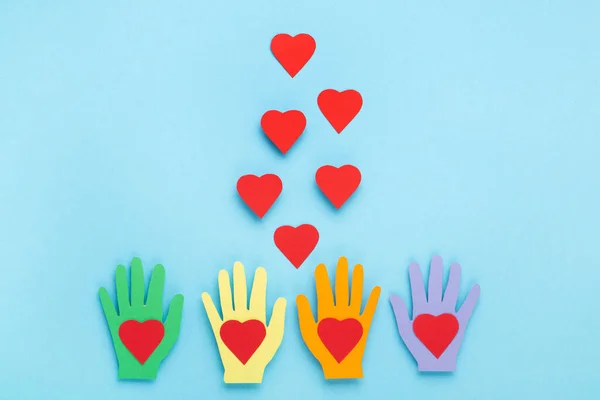 International Day of Charity, 5 September. Tolerance, kindness, cooperative, friendship, charity, humanitarian aid day concept. Colorful hands on blue background, copy space, top view.