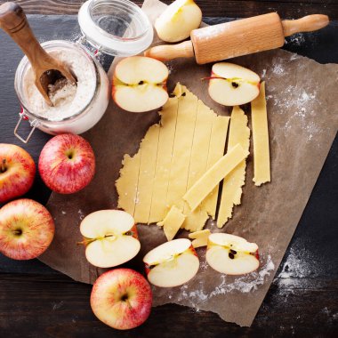 Ingredients for apple pie baking. Fresh red apples, butter, flour, brown sugar and spices on rustic wooden background.