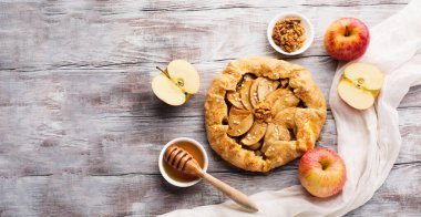 Homemade Apple Pie Galette with apples and honey on White rustic wooden background. Festive pastry for Thanksgiving day. Cozy holiday concept. Top view, copy space.