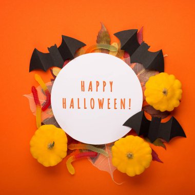 Turuncu arka planda Cadılar Bayramı kağıt süslemeleri. Siyah yarasalar, balkabakları ve sonbahar yaprakları. Cadılar Bayramı konsepti Düz yerde, üst tarafta. Fotokopi alanı olan Cadılar Bayramı partisi tebrik kartı maketi. 