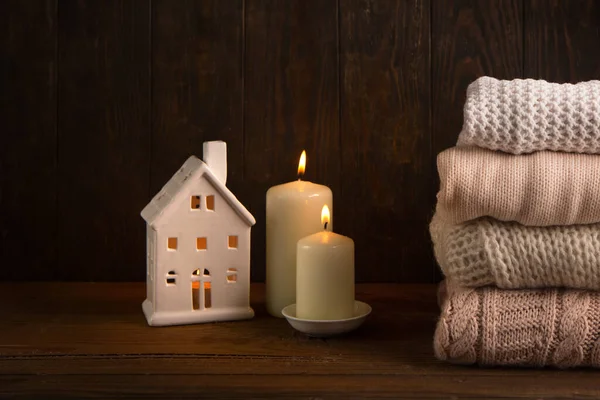 Winter house insulation, Energy saving, conservation, Save your money, Home heating and gas crisis, European energy crisis concept. Winter knitted sweaters and white candles on old wooden background.