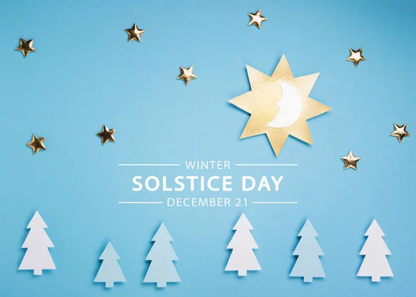 Winter solstice day holiday, December 21. Longest night in the year concept. Sun, moon and golden stars symbol on blue paper background. Flat lay, top view, copy space