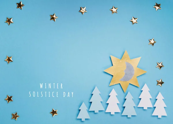 Winter solstice day holiday, December 21. Longest night in the year concept. Sun, moon and golden stars symbol on blue paper background. Flat lay, top view, copy space
