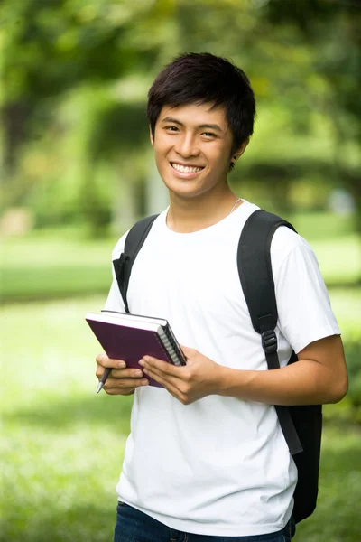 Asiatische schöne junge Kerl öffnen ein Buch und lächeln in den Park — Stockfoto