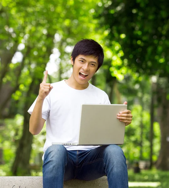 Asiático bonito jovem cara pensando com laptop no parque — Fotografia de Stock