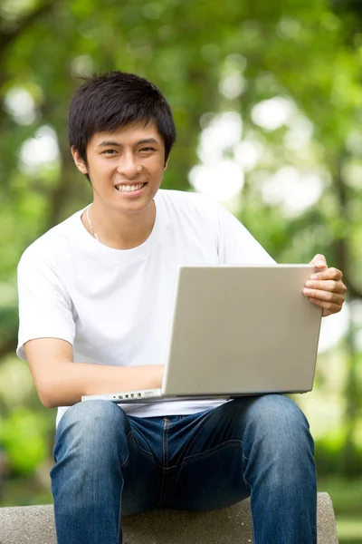 Asian handsome young guy with laptop in the park — Stock Photo, Image