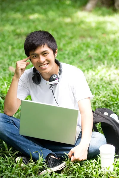 Asiatiska stilig ung kille med laptop i parken — Stockfoto