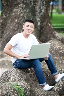 genç yakışıklı Asya öğrenci dizüstü parkta kullanma