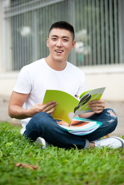 Asya yakışıklı genç öğrenci adam parkta kitap okumak — Stok fotoğraf