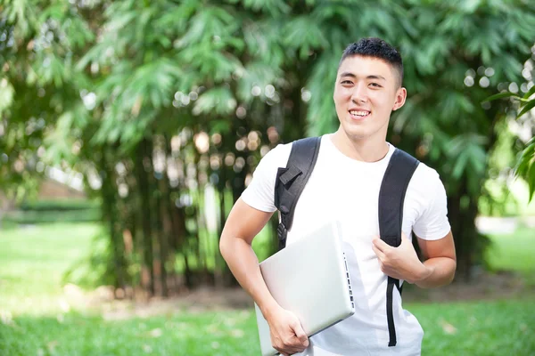 genç yakışıklı Asya öğrenci dizüstü parkta kullanma