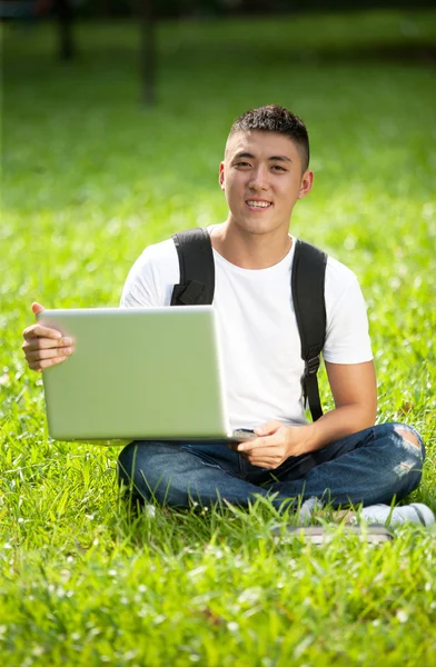 Young handsome asian student using laptop in the park — Stock Photo, Image
