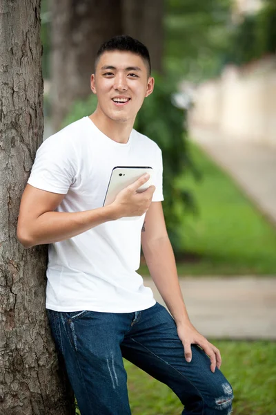 Portrait of young handsome asian student in the park — Stock Photo, Image
