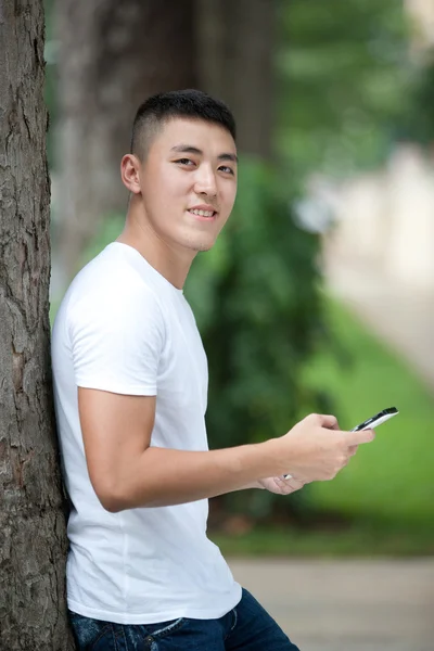 Portrait of young handsome asian student in the park — Stock Photo, Image