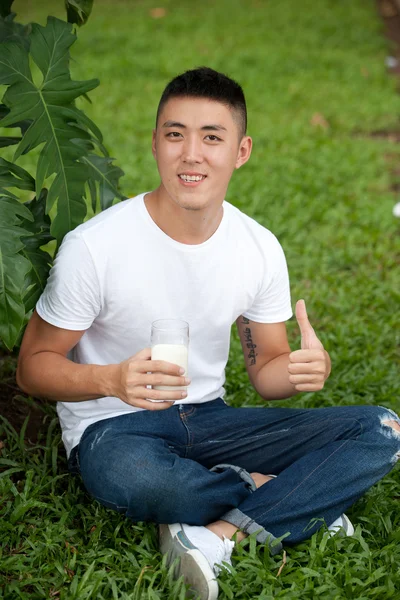 Asiatique bel étudiant homme boire un verre de lait dans le jardin — Photo
