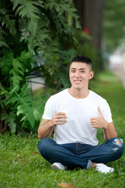 Asian handsome student man drink a glass of milk in the garden — Stock Photo, Image