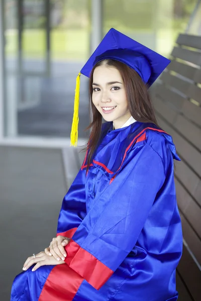 Portrait of a beautiful young asian woman in graduation cap and gown standing outside on campus — Stock Photo, Image