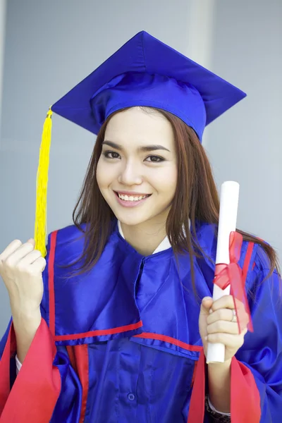 Portrait of a beautiful young asian woman in graduation cap and gown standing outside on campus — Stock Photo, Image