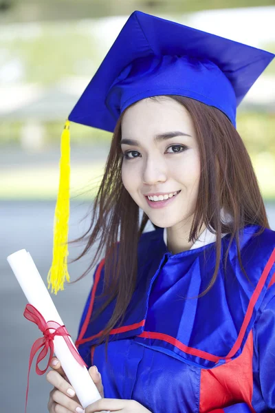 Mezuniyet kep ve kampüs dışında elbisesi ayakta içinde güzel bir genç Asyalı kadın portresi