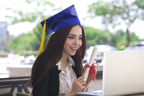 Happy businesswoman sitting at her workplace and smile with graduation cap — Stock Photo, Image