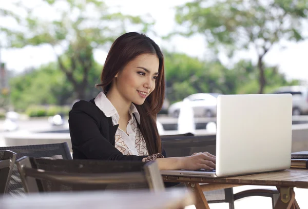 Uma mulher de negócios asiática bonita usando laptop ao ar livre — Fotografia de Stock