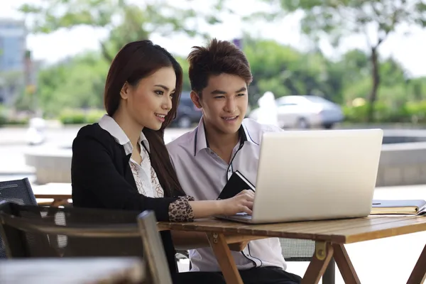 Asiatiska par använder laptop utomhus — Stockfoto
