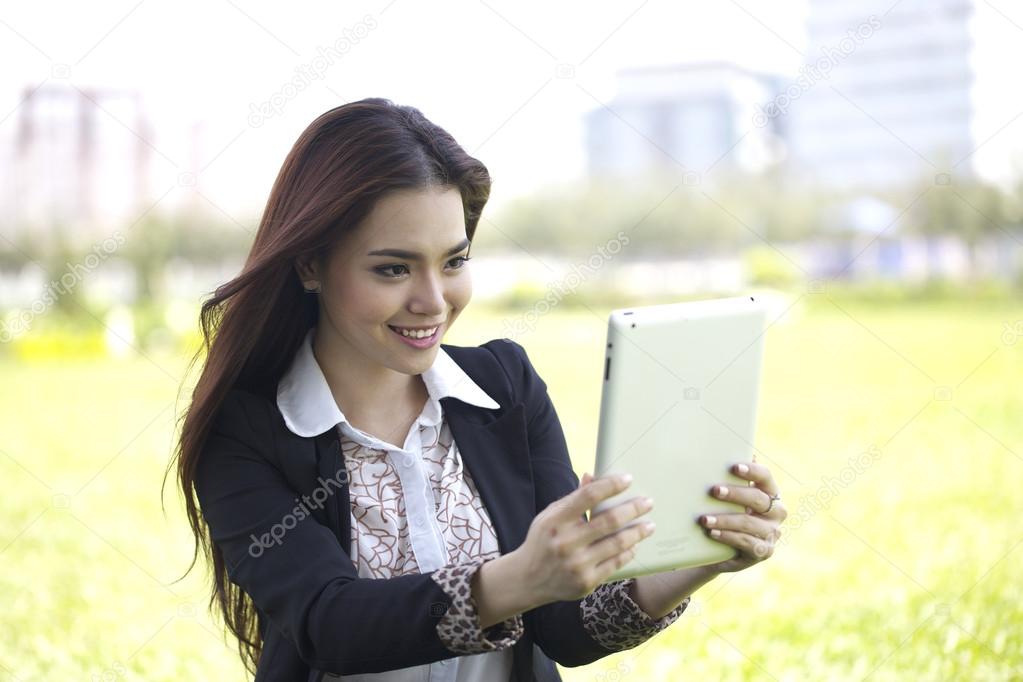 Beautiful Asian woman using iPad tablet to take photo