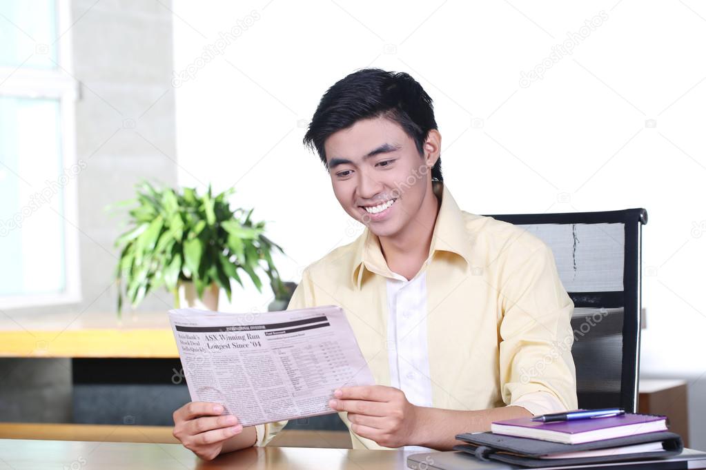 Happy asian young business man read newspaper and smile