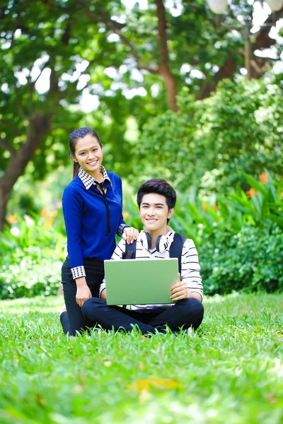 Jóvenes estudiantes asiáticos con computadora y sonrisa al aire libre —  Fotos de Stock