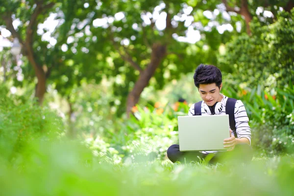 Giovane bello studente asiatico con computer all'aperto — Foto Stock