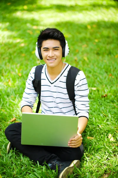 Young handsome Asian student with computer in outdoor — Stock Photo, Image