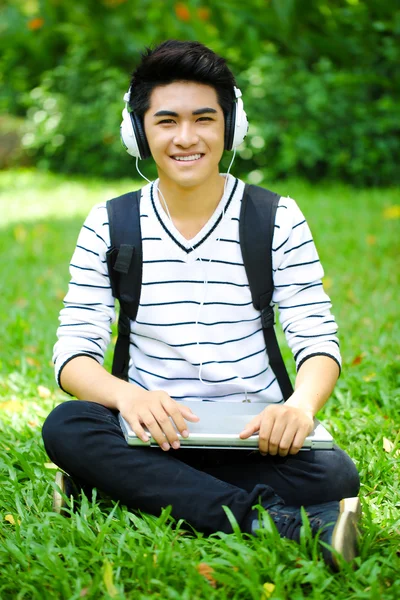 Молодой привлекательный азиатский студент с компьютером на открытом воздухе — стоковое фото