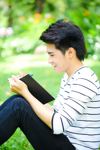 Giovane bello studente asiatico con libro all'aperto — Foto Stock