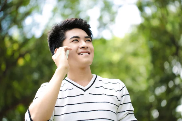 Young handsome Asian student with phone in outdoor — Stock Photo, Image