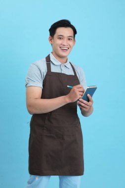 Garson üniformalı Asyalı yakışıklı adam, hoş geldin misafir ve sipariş, mavi arka planda izole.