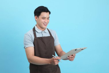 Garson üniformalı Asyalı yakışıklı adam, hoş geldin misafir ve sipariş, mavi arka planda izole.