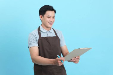 Garson üniformalı Asyalı yakışıklı adam, hoş geldin misafir ve sipariş, mavi arka planda izole.