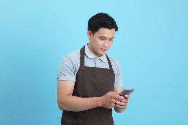 Garson üniformalı Asyalı yakışıklı adam, hoş geldin misafir ve sipariş, mavi arka planda izole.