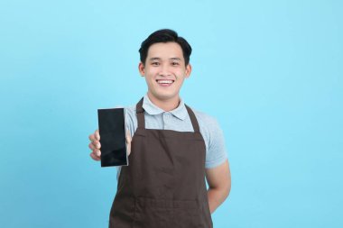 Garson üniformalı Asyalı yakışıklı adam, hoş geldin misafir ve sipariş, mavi arka planda izole.